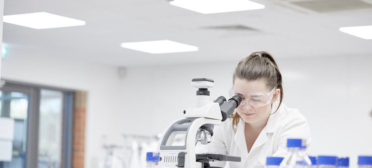 Female Student In Lab Using Microscope