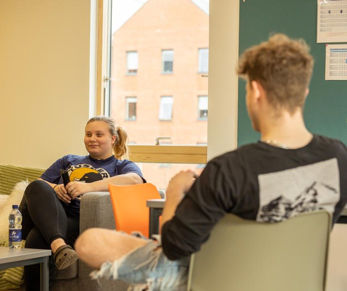 Blackfriars living space, a male and female student sat opposite chatting