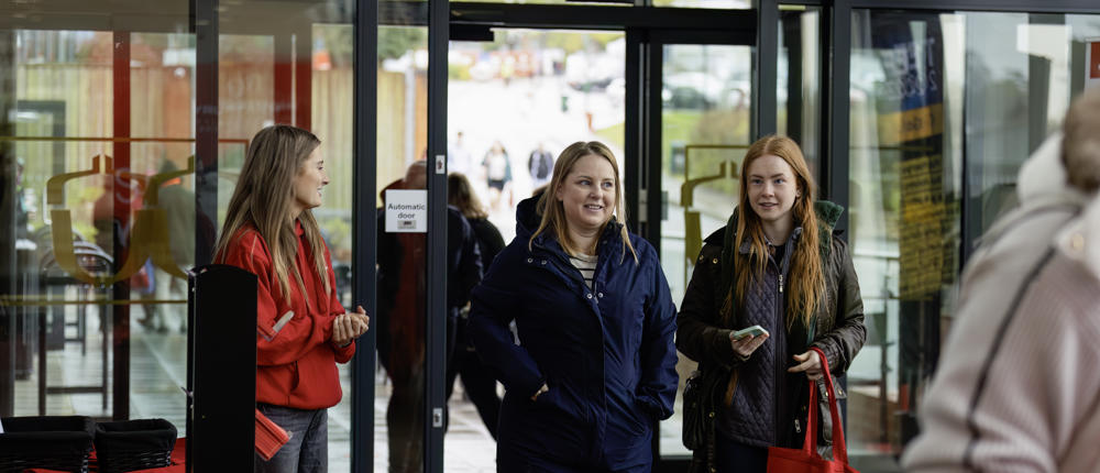 Visitors Walking Through Doors With Gift Bag