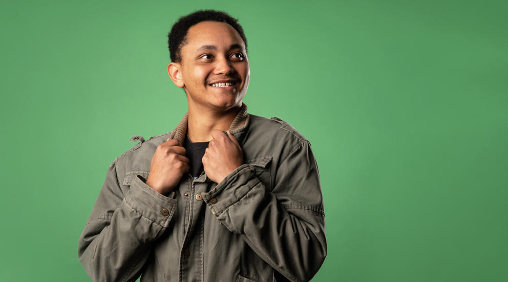 Image of international student smiling to their left whilst holding the collar of their jacket
