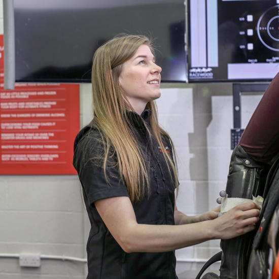 Lady Helping A Rider On Horse Simulator