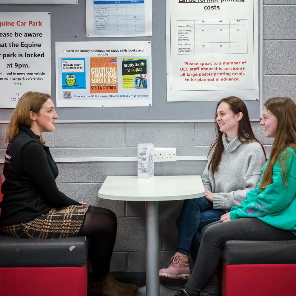 Student Support staff member sat with two students